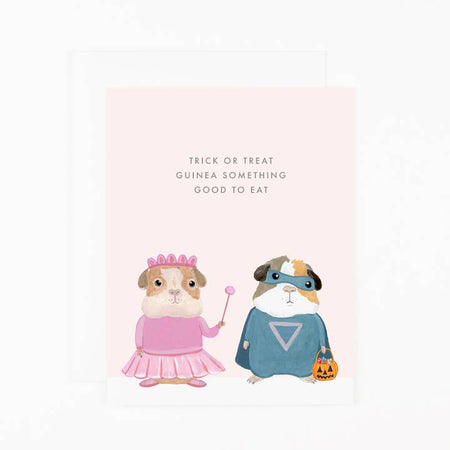 Light pink card with image of two guinea pigs dressed up in Halloween costumes: one as a princess and one as a superhero. Gray text saying, “Trick or Treat Guinea Something Good to Eat”. A white envelope is included.