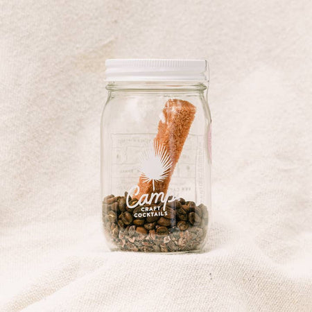 Cocktail jar with espresso beans and a sugar cane stick.