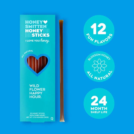 Honey sticks packaged in a vertical blue box with a heart shape cut out in center. White text saying, “Honey Smitten Honey Sticks Wildflower Happy Hour”.