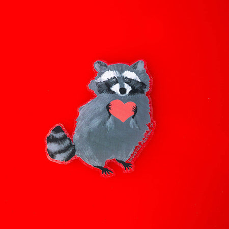 Sticker in the image of a raccoon holding a red heart.