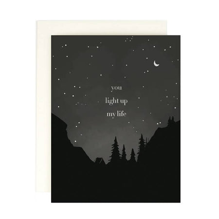 Black card with night sky background with white stars, white half moon, and outline of forest trees. White text saying, 