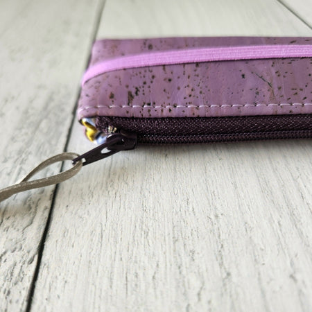 Cork rectangle pencil case in purple color with purple zipper and purple banding along the bottom center. Brown twine loop attached to zipper.