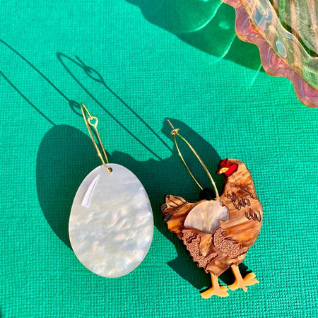 Set of earrings with one being a white egg and the other a brown chicken.