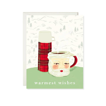 White card with image of pinetree scene wallpaper in background with a vintage plaid thermos and Santa Claus mug sitting on a green table. White text saying, “Warmest Wishes”. A white envelope is included.