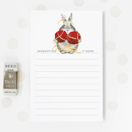 White list notepad with image of a gray bunny holding spaghetti and meatballs. Gray text saying, “Spaghetting It Done”.