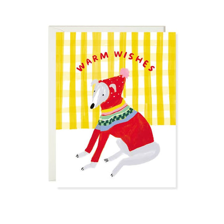 White card with yellow and white vertical stripes. Red text saying, “Warm Wishes”. Image of a greyhound dog sitting wearing a red hooded winter sweater with a pink pom-pom on top. A white envelope is included.