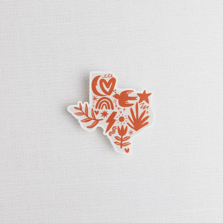 White sticker in the shape of Texas with orange images of a sun, moon, stars, dove, flower, rainbow, heart and lightning bolt.