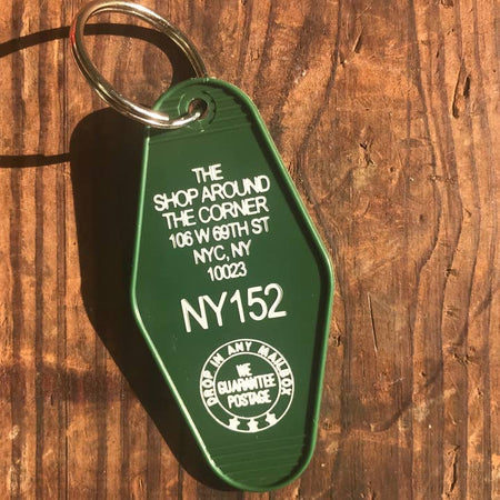 Green vintage style motel key fob with white text featuring the iconic bookstore from You've Got Mail.