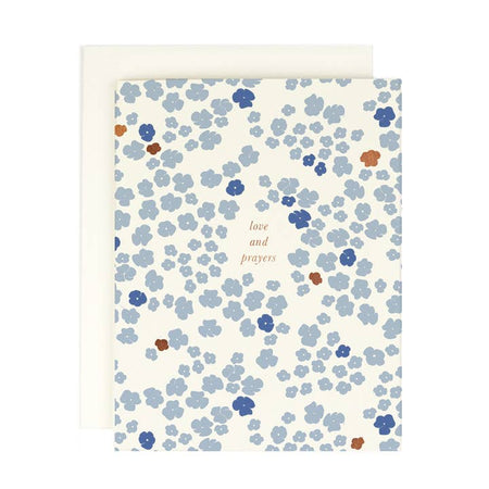 White card with tiny blue and orange flowers in background. Gold foil text saying, 