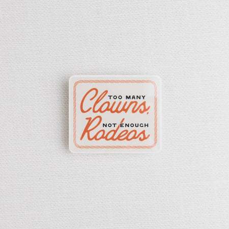 Ivory sticker with orange braided border and black and orange text saying, “Too Many Clowns Not Enough Rodeos”.