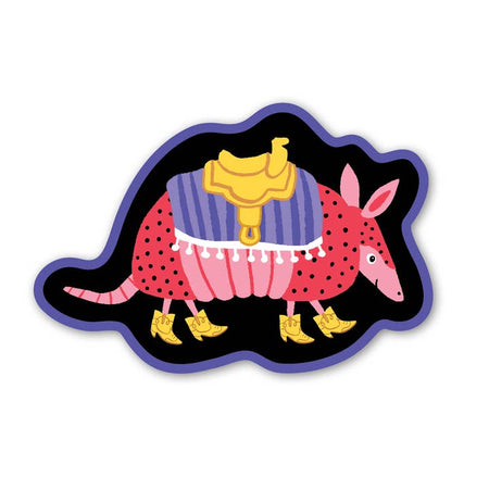 Black background sticker with image of a pink armadillo wearing a purple blanket, yellow saddle and yellow cowboy boots.