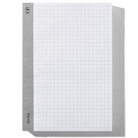 Notebook with gray fabric spine on left side. White graph paper.