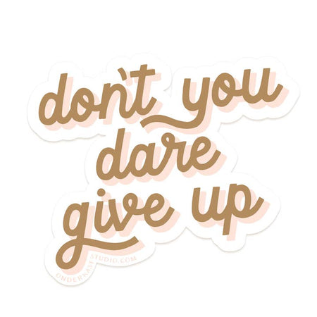 Sticker with brown script text outlined in pink saying, “Don’t You Dare Give Up”.