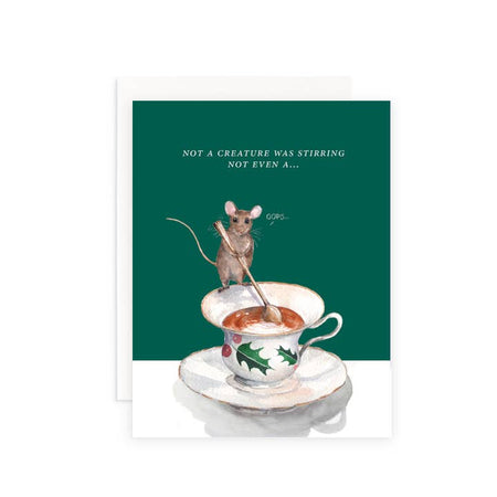 Green background card with white text saying, “Not a Creature was Stirring Not Even A….” Image of a mouse stirring a cup of tea inside of a fancy Christmas teacup with holly design. A white envelope is included.