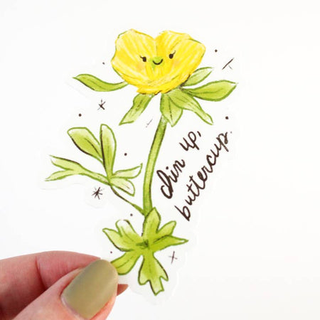 Sticker in the image of a yellow buttercup flower with black text saying, “Chin Up Buttercup”.