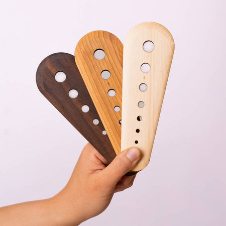 Wooden spatula with various sized holes for used for stripping herbs.