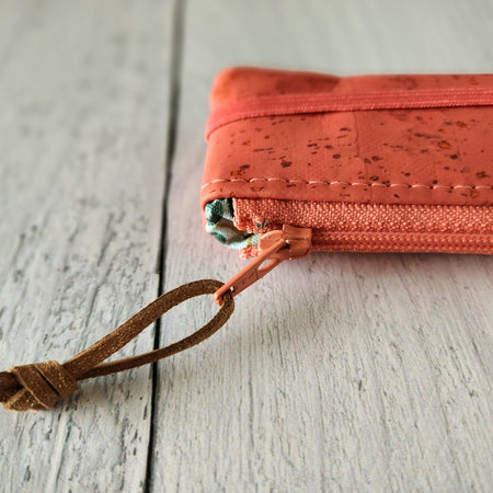 Cork rectangle pencil case in pink coral color with coral zipper and coral banding along the bottom center. Brown twine loop attached to zipper.