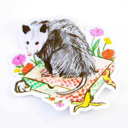 Image of a possum sitting on top of a pizza box. Colorful flowers in background.