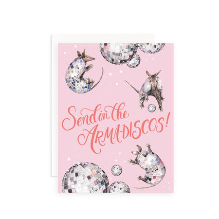 Pink card with dark pink text saying, “Send in the Arma-Discos!” Images of several armadillos with disco balls as their shell and disco balls scattered across card. A white envelope is included.