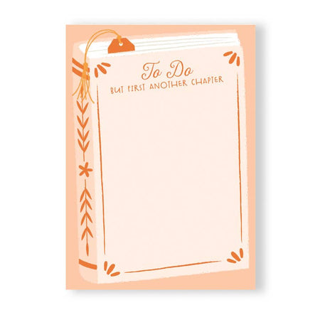 Light pink notepad with a pink and orange novel book in center. Orange text at top center saying, “TO DO But First Another Chapter”.