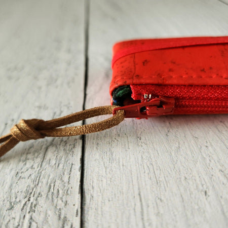 Cork rectangle pencil case in red color with red zipper and red banding along the bottom center. Brown twine loop attached to zipper.