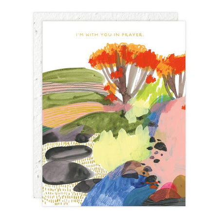 White card with muted images of a scenic vista with rocks, bushes, trees, valley, and mountains. Yellow text saying, “I’m With You in Prayer”. A matching envelope is included.