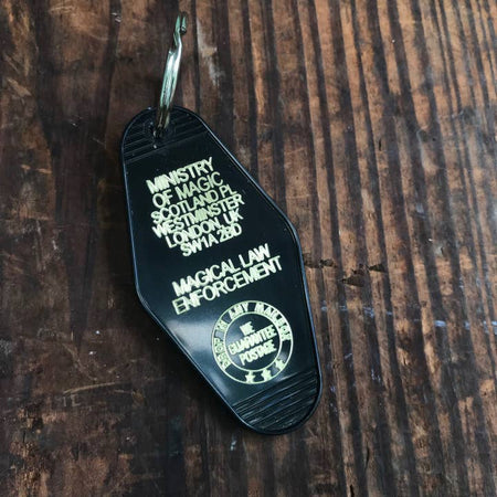 Black vintage style motel key fob with gold text featuring keys to the Magical Law Enforcement office in the Harry Potter universe.