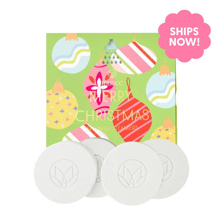 White soap discs wrapped in a green box with images of various Christmas tree ornaments with gold foil text saying, ,”Merry Christmas Shower Steamers”.