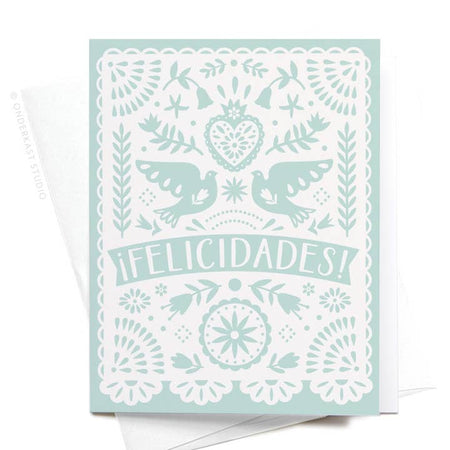 Teal card with white doilie lace design in center. Images of hearts, flowers, and birds in pattern. White text saying, “Felicidades!”. A white envelope is included.