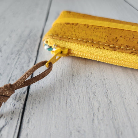 Cork rectangle pencil case in yellow color with yellow zipper and yellow banding along the bottom center. Brown twine loop attached to zipper.