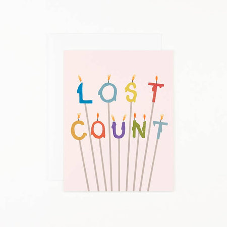 Pink card with colored number and letter candles on individual sticks saying, “Lost Count”. A matching envelope is included.