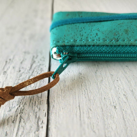 Cork rectangle pencil case in teal color with teal zipper and teal banding along the bottom center. Brown twine loop attached to zipper.