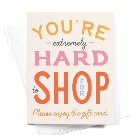 White card with yellow, pink, red, black, blue and orange text saying, “You’re Extremely Hard to Shop For. Please enjoy the gift card.” A white envelope is included.