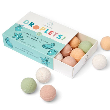 Multicolored bath balls packaged in a white box with water and wave background with muted images of fruits. Rainbow text saying, “Droplets Mixable Bath Bombs”.