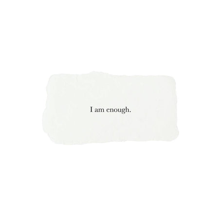 Ivory rectangle with torn edges and black text saying, “I am Enough”.