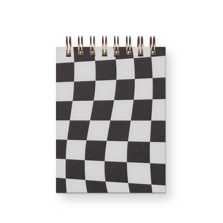 Notebook with black and whtie checkerboard pattern on cover. Gold coil binding across top.