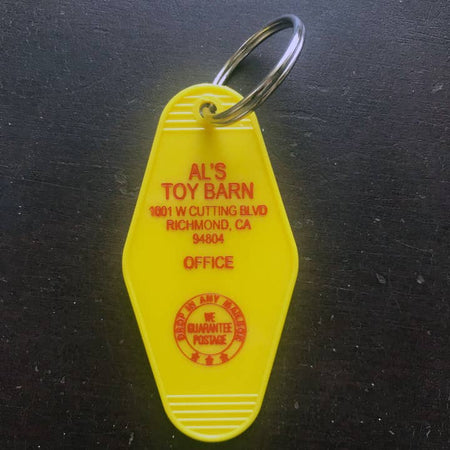 Yellow vintage style motel key fob with red text featuring Al's Toy Barn from Toy Story.