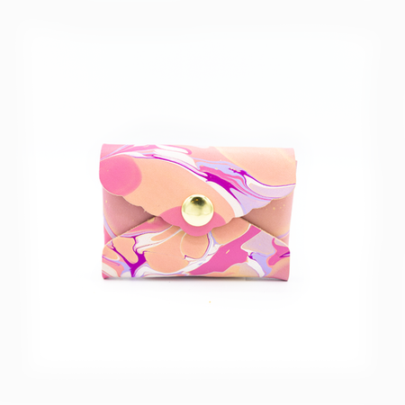 Small leather envelope with colorful marble swirl design in pinks, purples and oranges with brass snap in center.